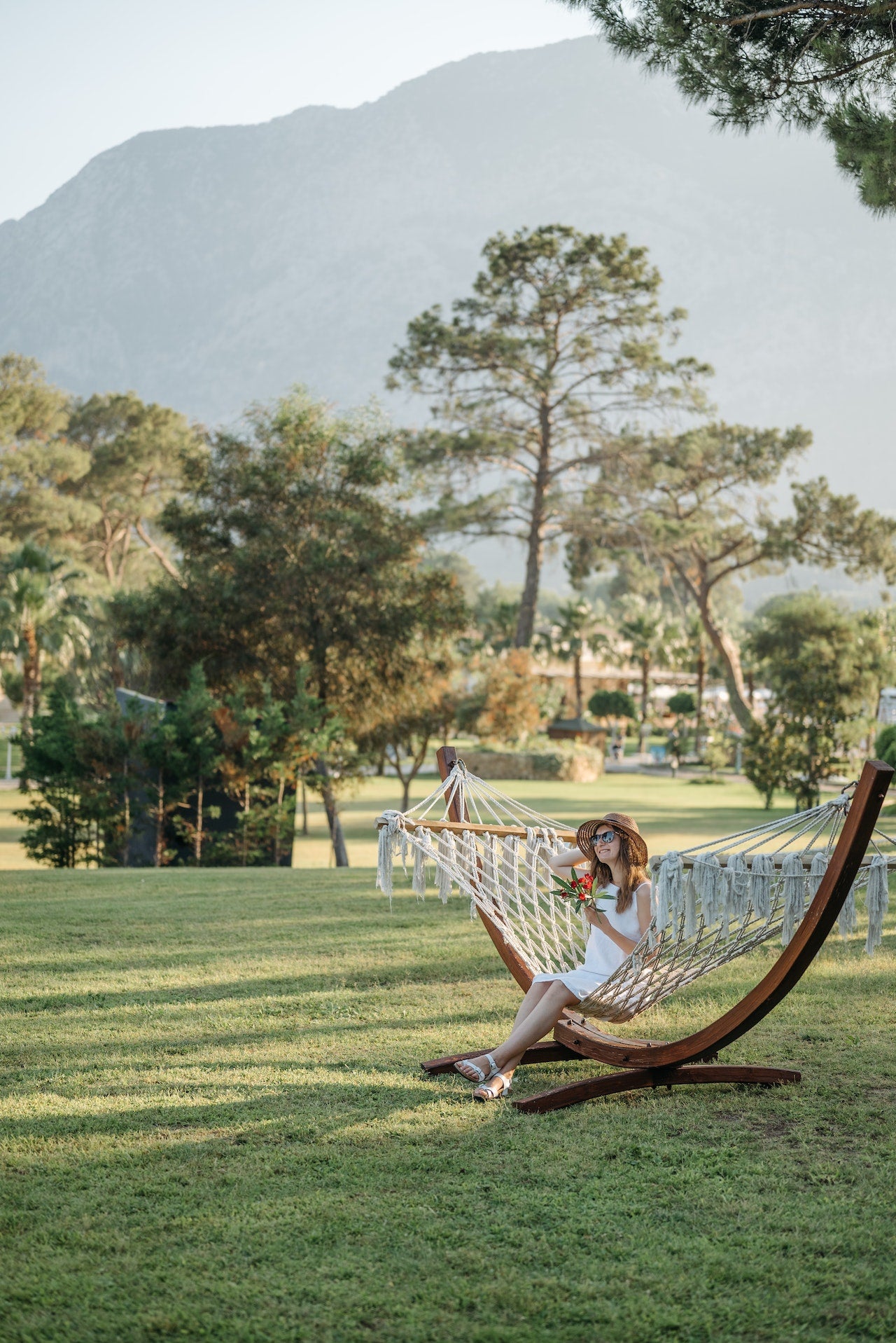 Woman in White Dress With Hat Sitting on Hammock on Grass Field